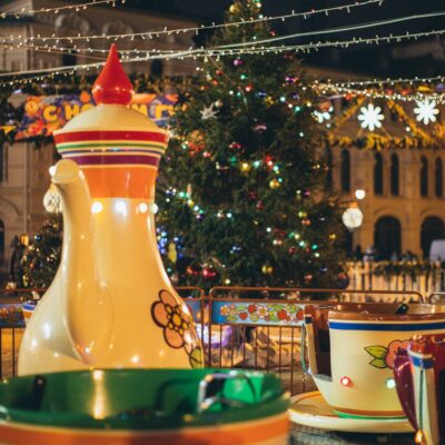 Merry go round with large colorful traditional Russian teapot and cups in city park decorated in New Year style in evening