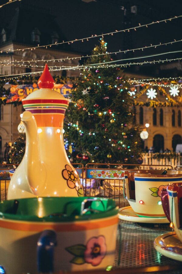 Merry go round with large colorful traditional Russian teapot and cups in city park decorated in New Year style in evening