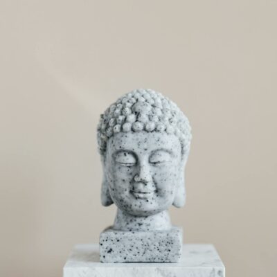 Stone bust of Buddha on marble stand